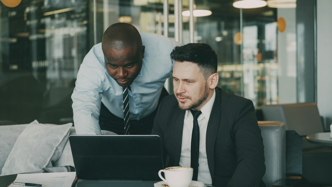 Two business partners comparing information on a laptop